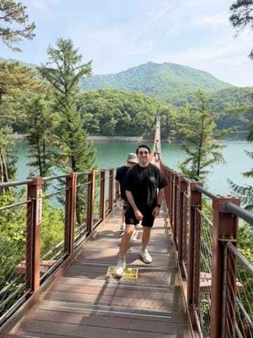 Matt walking across a suspension bridge above a lake