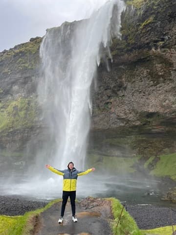 Matt standing with arms outstretched in front of a waterfall